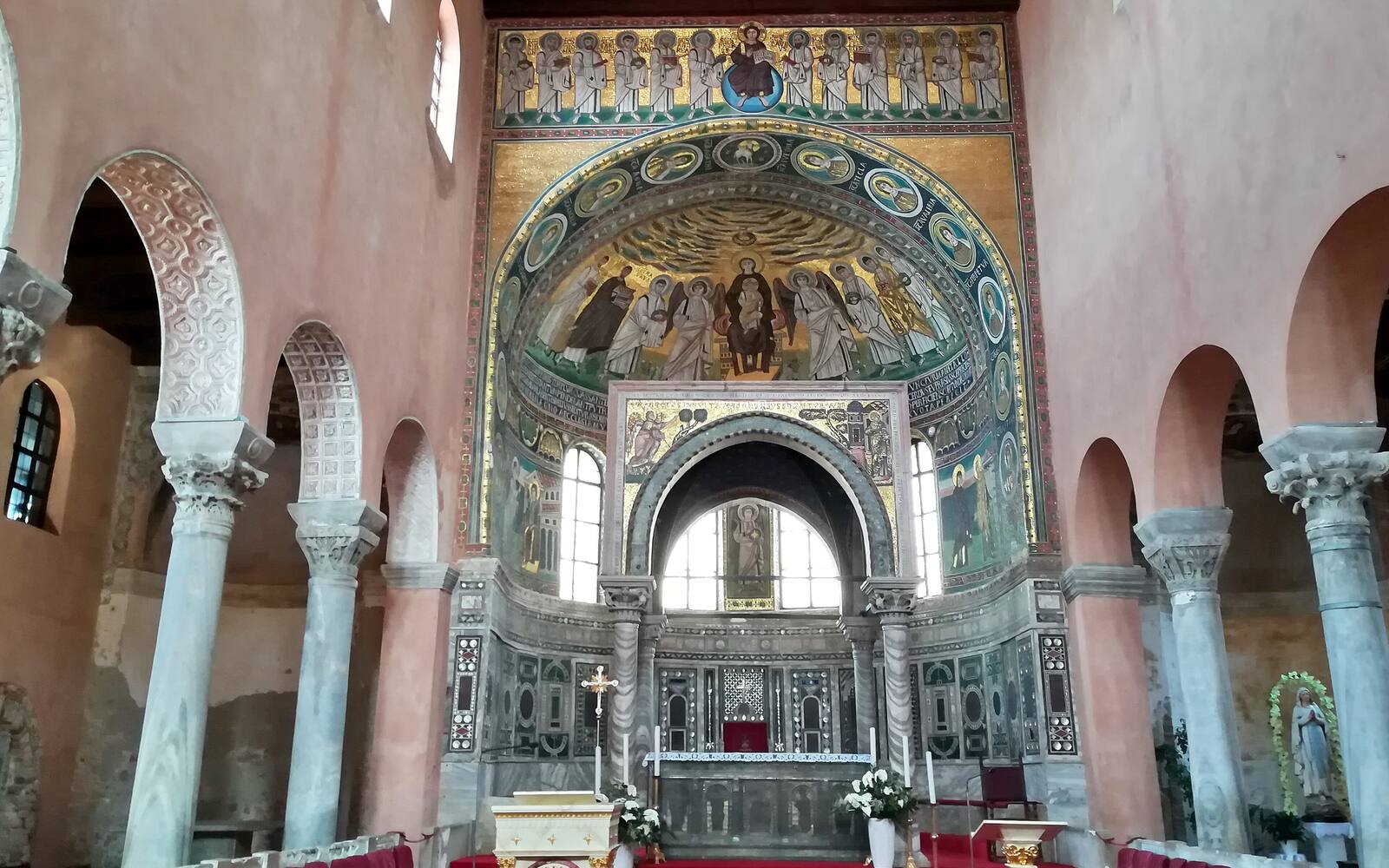 Interieur van de Euphrasiusbasiliek in Poreč met zuilenrijen en goudkleurige Byzantijnse mozaïeken in de apsis