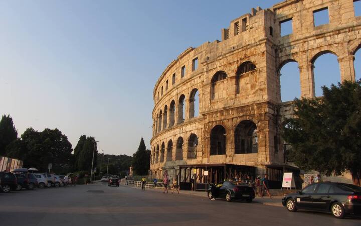 De Romeinse arena van Pula met zijn drie verdiepingen stenen bogen, gezien vanaf de straat bij avondlicht