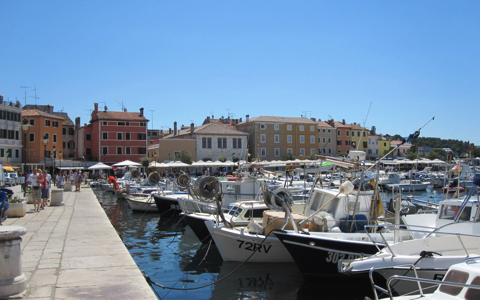 De haven van Rovinj met vissersboten en sloepen langs de kade en kleurrijke huizen op de achtergrond