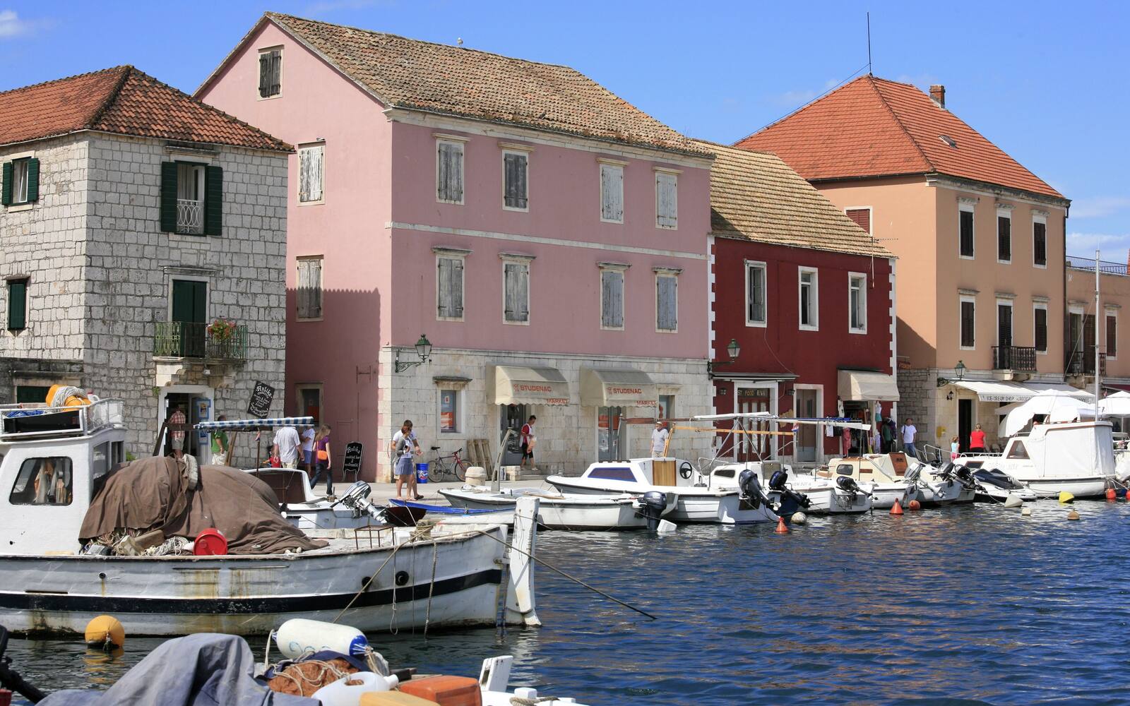 Haven van Stari Grad op Hvar met stenen huizen, cipressen en bootjes in het warme avondlicht