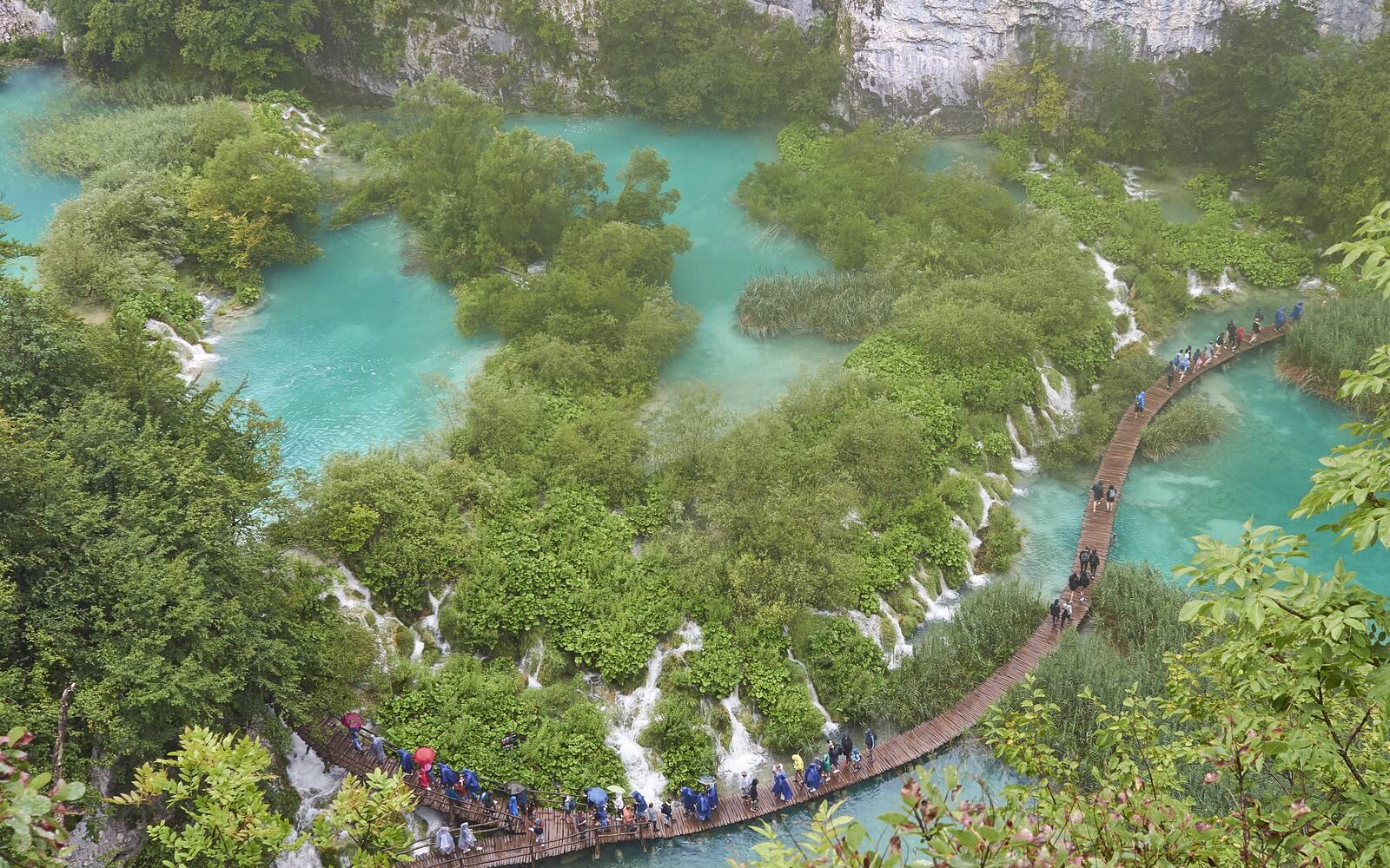 Luchtfoto van turquoise meertjes en watervallen in de Plitvicemeren met een houten vlonderpad door het groen