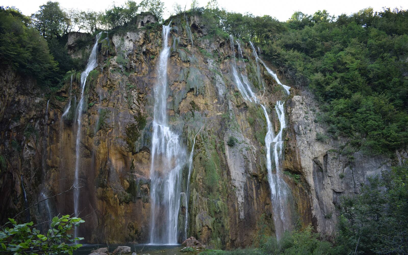 De Veliki slap, de hoogste waterval van de Plitvicemeren, die over een begroeide rotswand naar beneden stort
