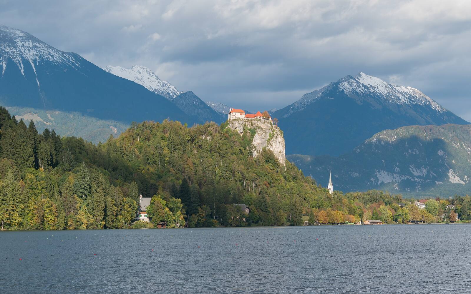 Het kasteel van Bled op een rots boven het meer, met besneeuwde bergtoppen van de Julische Alpen erachter